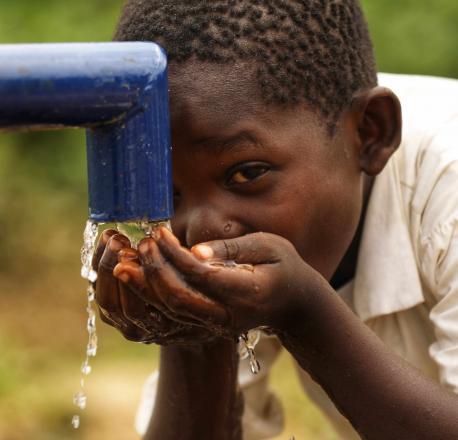 A boy drinks clean drinking water at a newly-installed hand pump